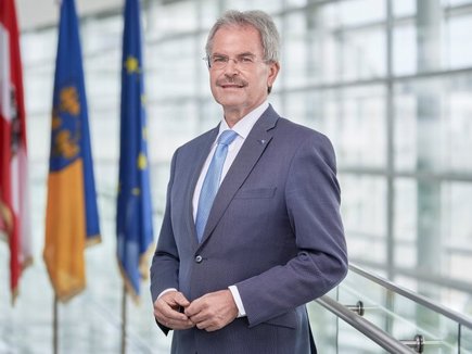 Präsident Karl Wilfing im NÖ Landtag; im Hintergrund die Fahnen Österreichs, Niederösterreichs und der EU